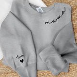 Grauer Sweater mit Mama Schriftzug und Kindernamen auf dem Ärmel - Personalisiertes Geschenk von Love & Faith